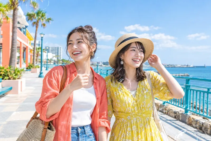 海辺の遊歩道で笑う友人2人の横長写真へ虹色のシャボン玉を加えたAnimated WebPの完成例